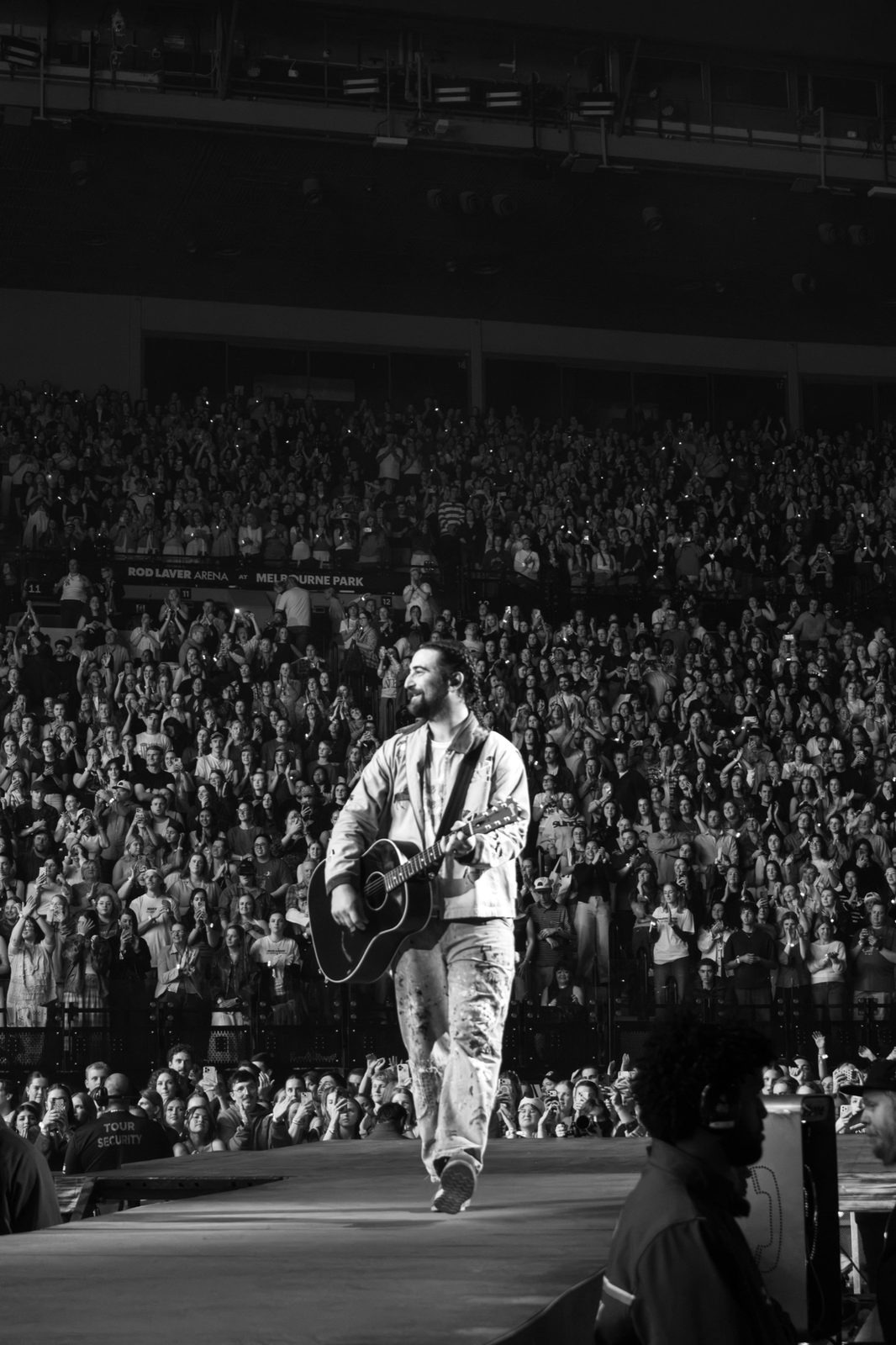 Black and white: performer walking the runway into a packed arena