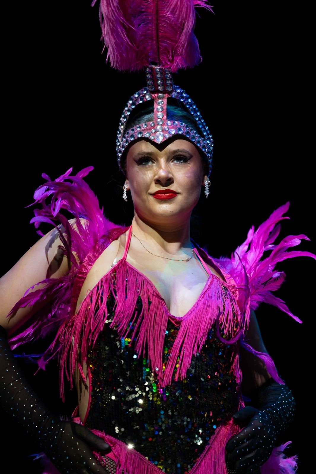 Showgirl in a pink feathered costume and jewelled headdress, close up